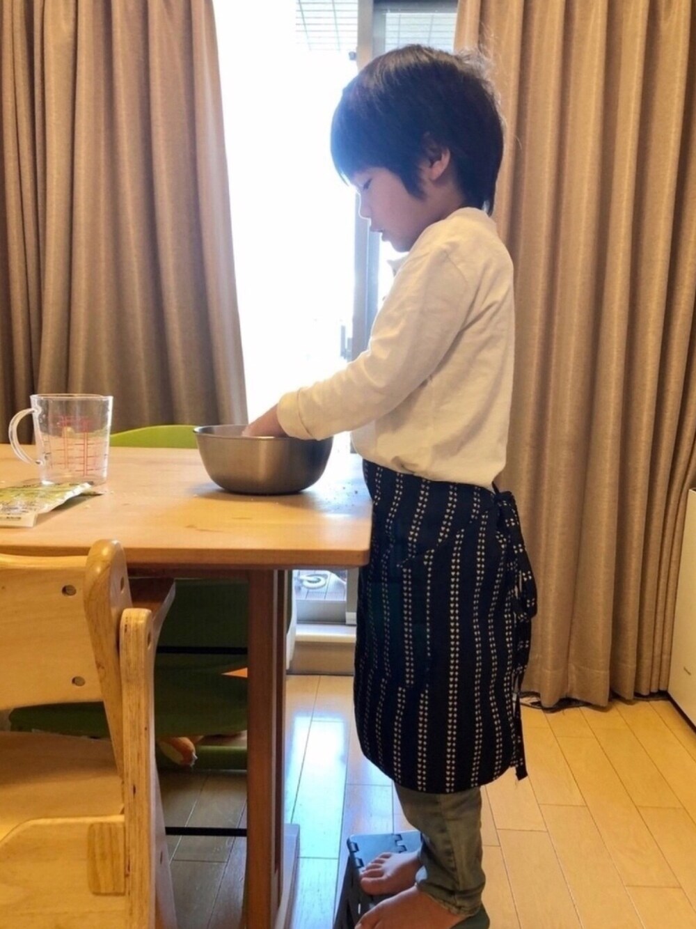 ブルー系のデニムパンツ、ホワイト系のシャツ/ブラウス、ブラック系のエプロンを着用したキッズの春コーディネートの1枚目の写真