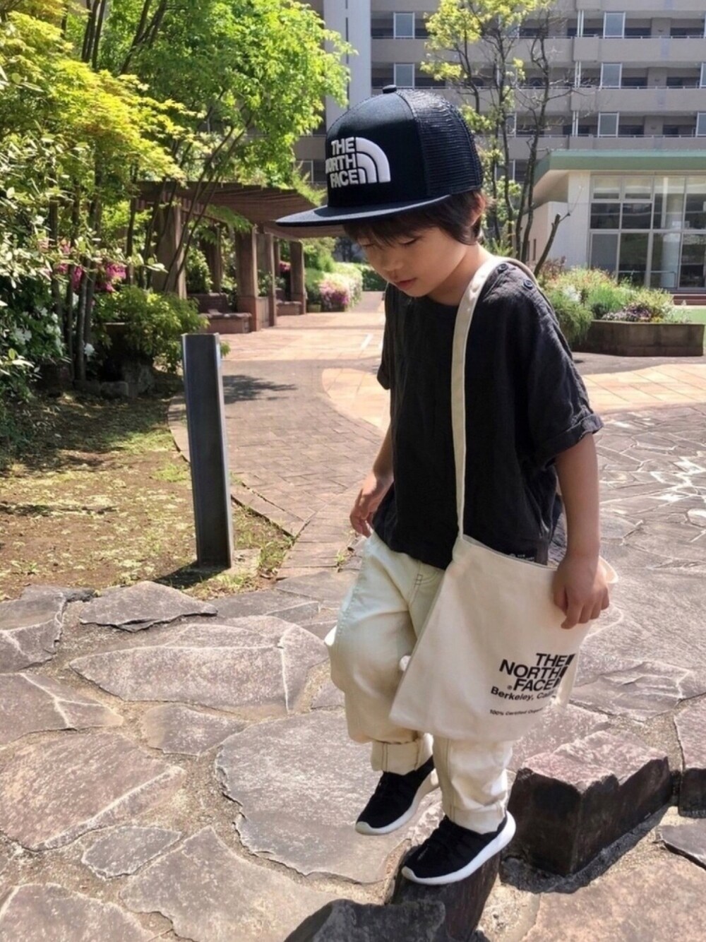 ブラック系のショルダーバッグ、ブラック系のTシャツ/カットソー、ホワイト系のデニムパンツを着用したキッズの春コーディネートの1枚目の写真