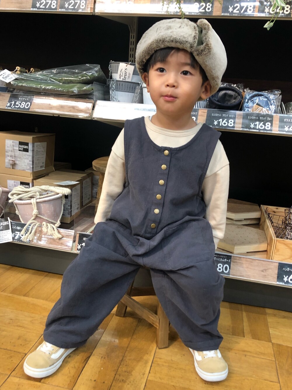 ベージュ系のスウェット、グレー系のオールインワン・サロペット、ベージュ系のスニーカーを着用したキッズの秋コーディネートの1枚目の写真