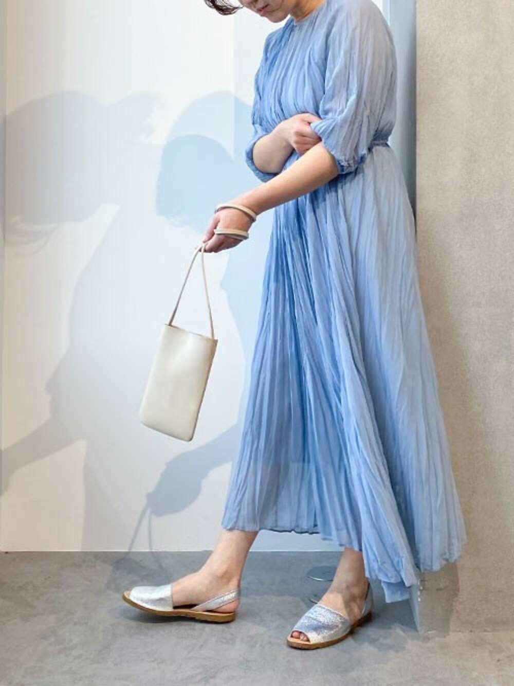 ブルー系のワンピース、ベージュ系のショルダーバッグを着用したレディースの春コーディネートの1枚目の写真