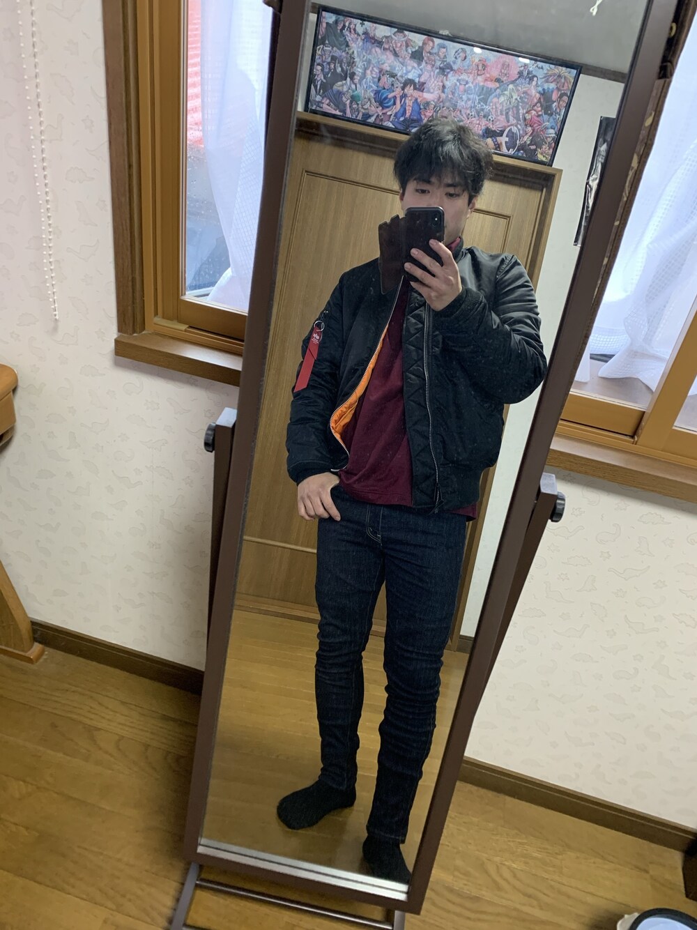 ブラック系のデニムパンツ、ブラック系のMA-1、レッド系のTシャツ/カットソーを着用したメンズの冬コーディネートの1枚目の写真