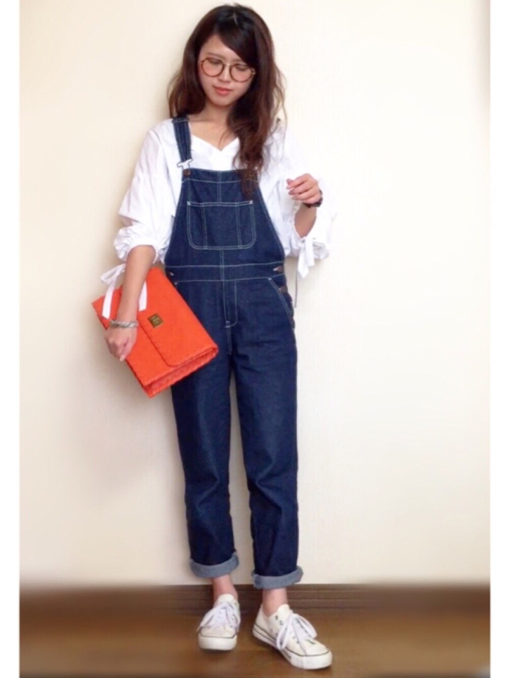 オレンジ系のショルダーバッグ、ホワイト系のシャツ/ブラウス、ブルー系のオールインワン・サロペットを着用したレディースの春コーディネートの1枚目の写真