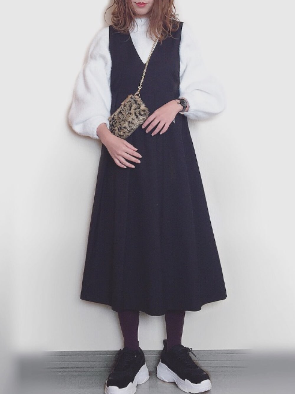 ホワイト系のニット/セーター、ブラック系のジャンパースカート、ブラック系のアナログ腕時計を着用したレディースの冬コーディネートの1枚目の写真