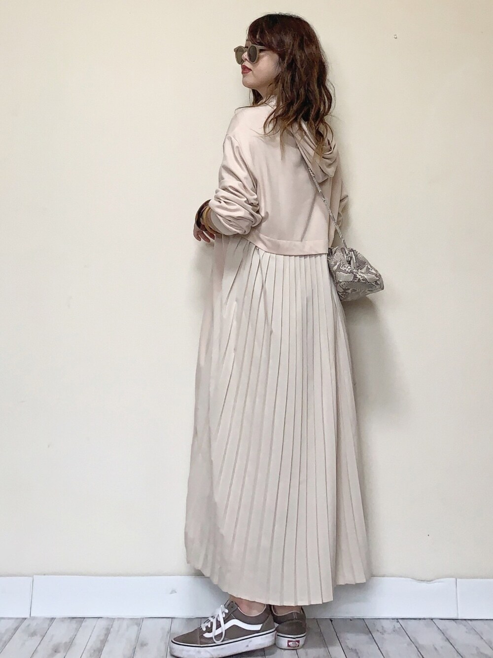 ベージュ系のワンピース、その他のクラッチバッグ、ベージュ系のスニーカーを着用したレディースの春コーディネートの1枚目の写真