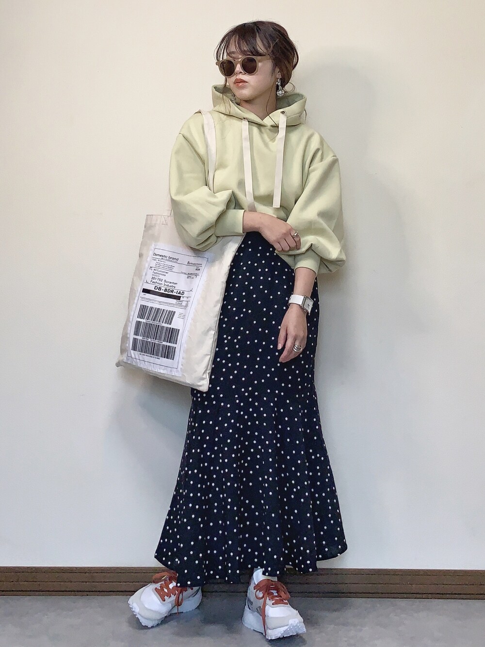 グリーン系のパーカー、ブラック系のスカート、ホワイト系のスニーカーを着用したレディースの冬コーディネートの1枚目の写真