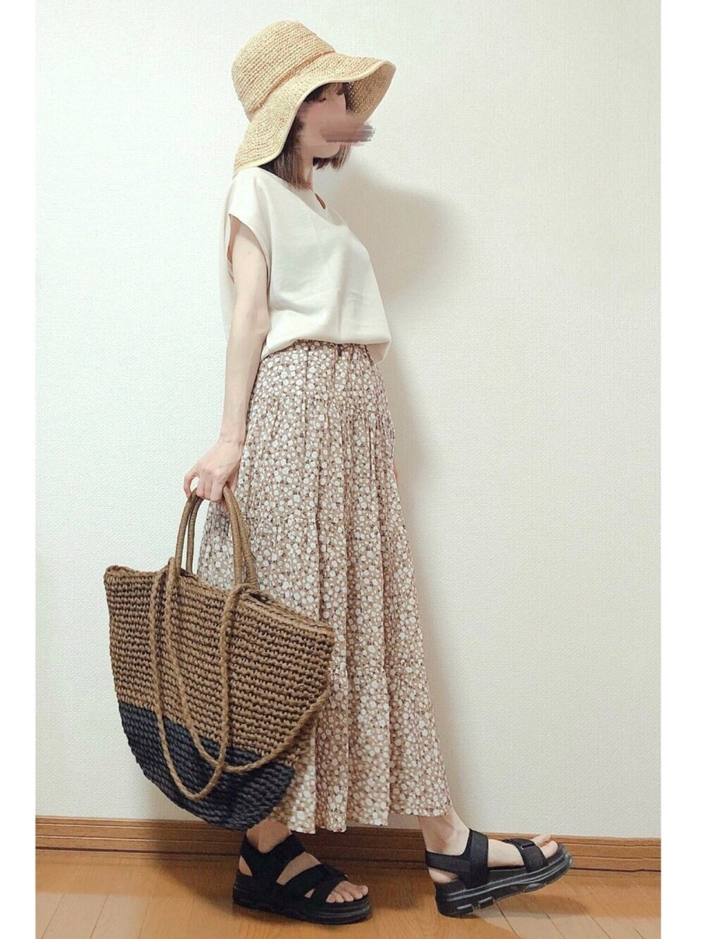 ベージュ系のスカート、ブラック系のサンダル、ブラウン系のかごバッグを着用したレディースの夏コーディネートの1枚目の写真