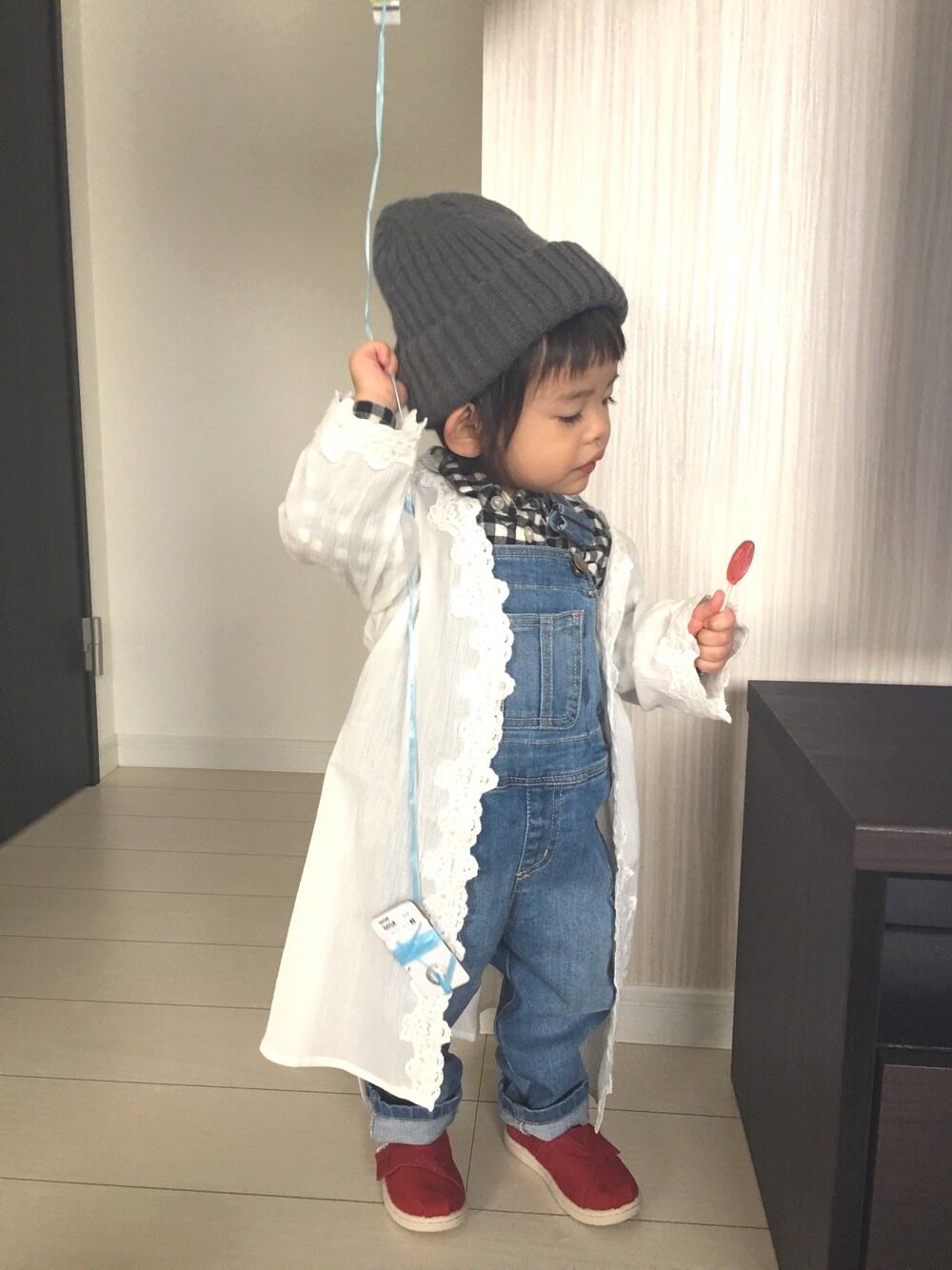 ホワイト系のカーディガン/ボレロ、ブルー系のサロペット/オーバーオール、レッド系のスニーカーを着用したキッズの春コーディネートの1枚目の写真