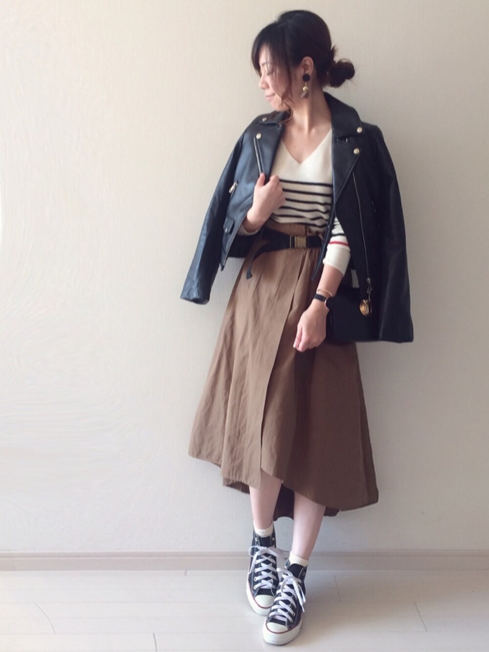 ブラック系のライダースジャケット、ブラック系のスニーカー、イエロー系のスカートを着用したレディースの秋コーディネートの1枚目の写真