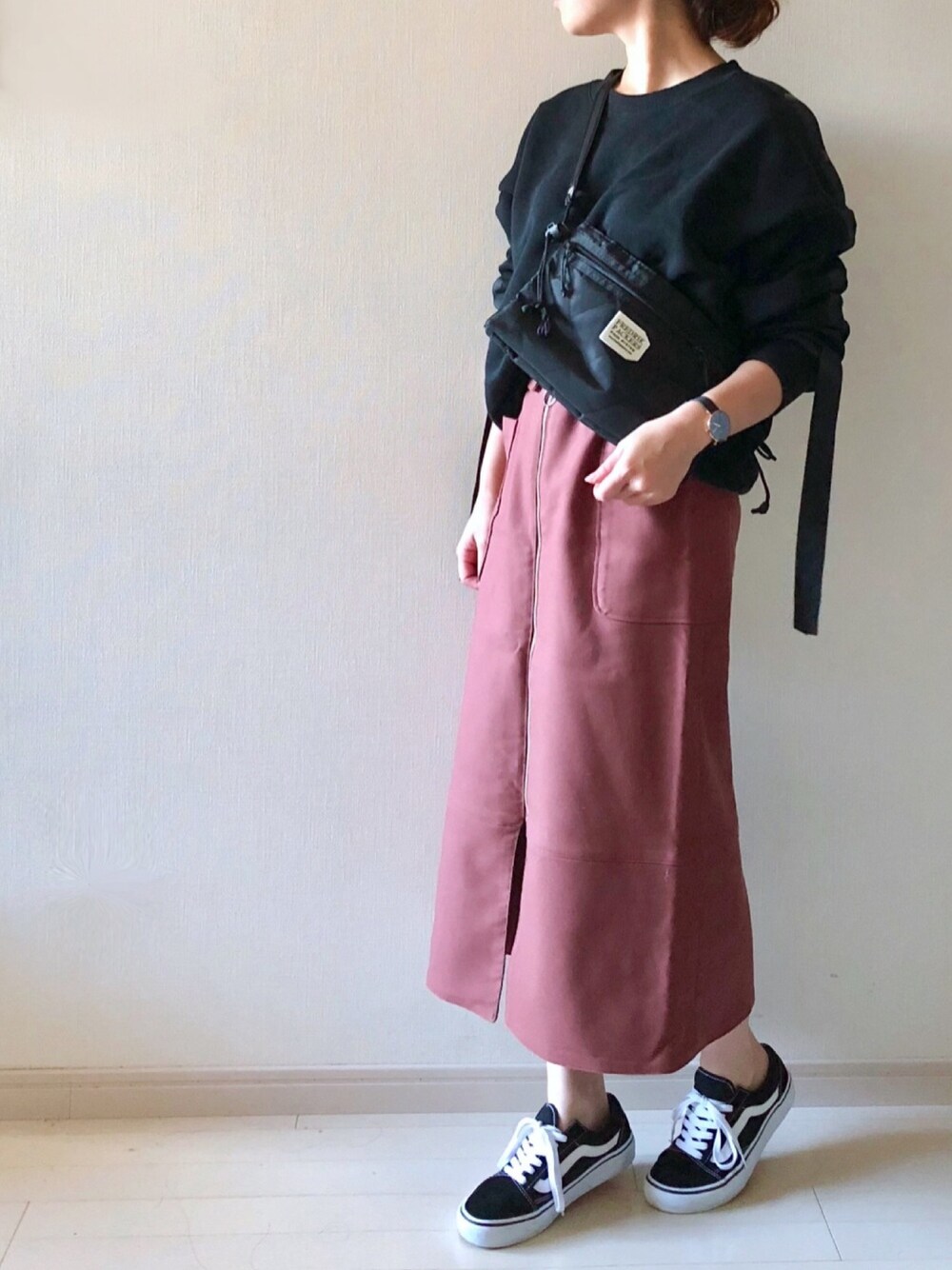 ブラック系のスウェット、ブラック系のスニーカー、ブラウン系のスカートを着用したレディースの秋コーディネートの1枚目の写真