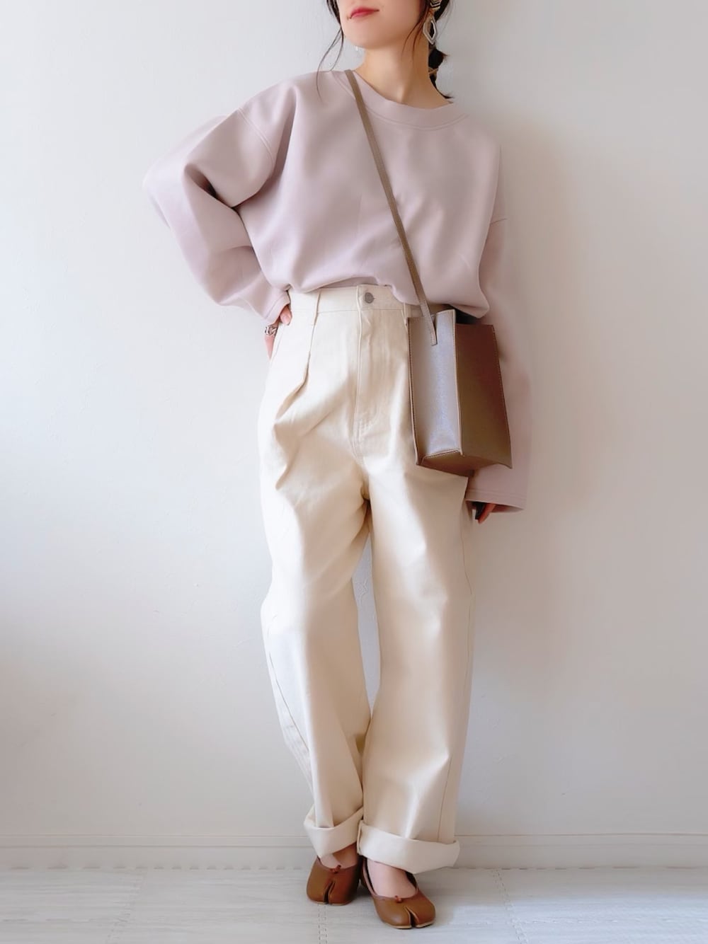 ホワイト系のデニムパンツ、グレー系のスウェット、ブラウン系のショルダーバッグを着用したレディースの春コーディネートの1枚目の写真