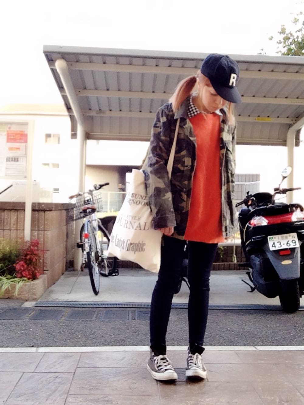 オレンジ系のニット/セーター、ブルー系のデニムパンツ、グリーン系のミリタリージャケットを着用したレディースの春コーディネートの1枚目の写真