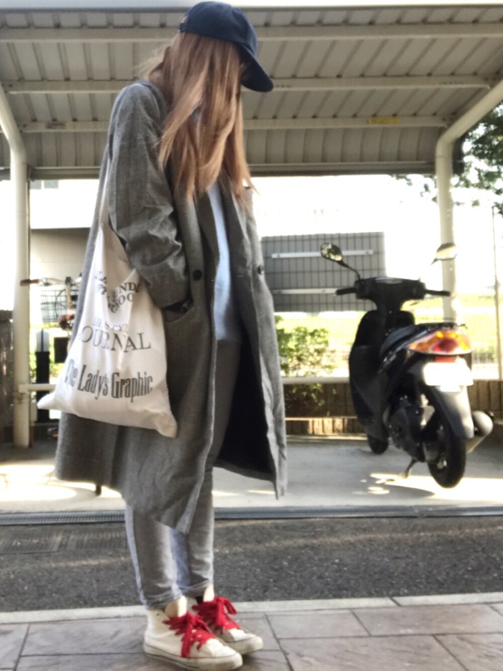 ブルー系のニット/セーター、ブラック系のステンカラーコート、ホワイト系のトートバッグを着用したレディースの春コーディネートの1枚目の写真