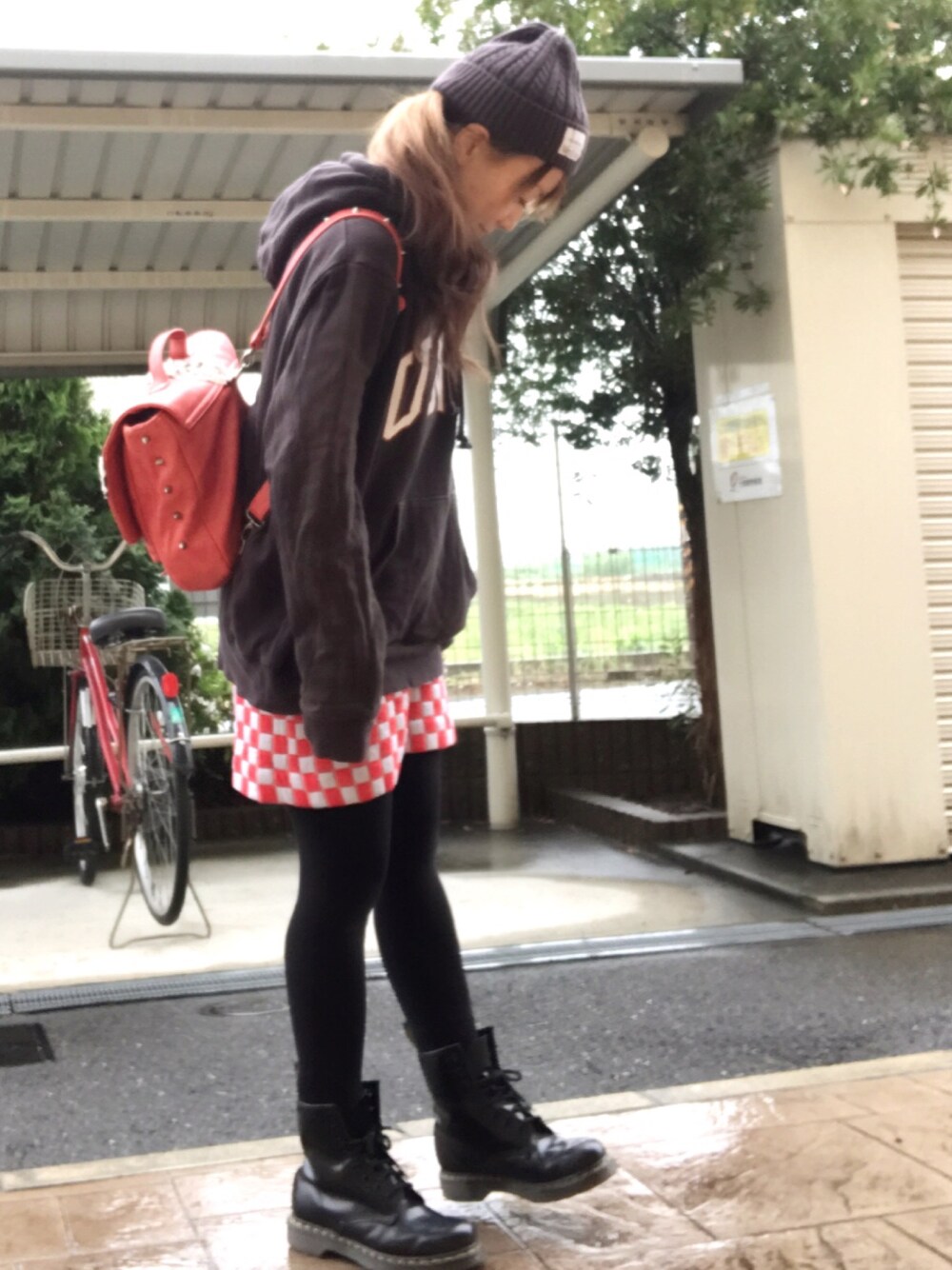 レッド系のショルダーバッグ、グレー系のスウェット、レッド系のスカートを着用したレディースの春コーディネートの1枚目の写真