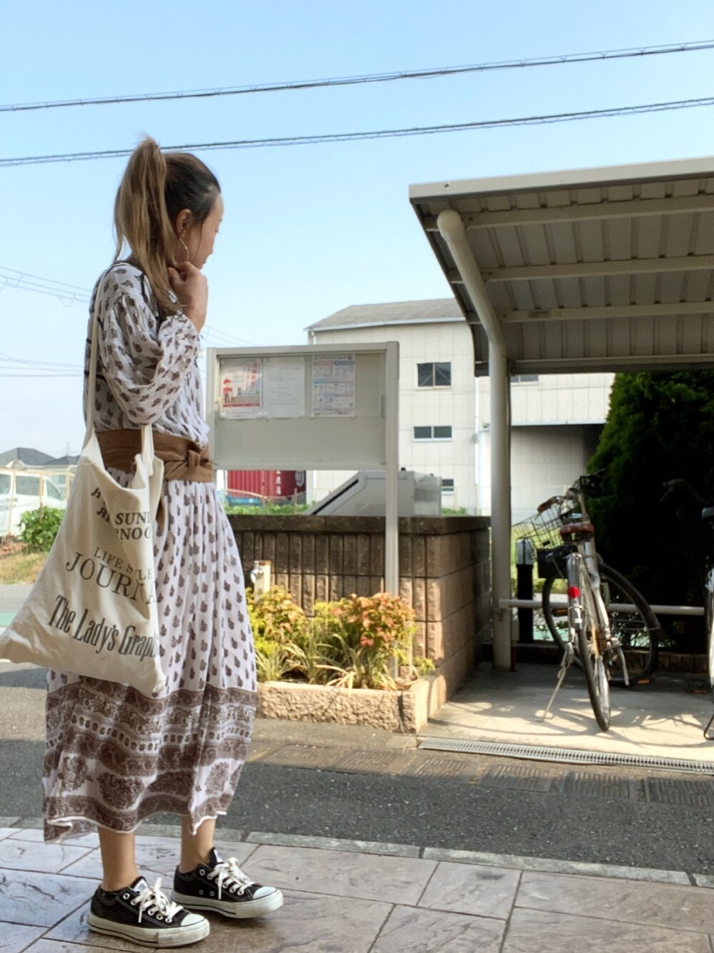 ベージュ系のワンピース、ホワイト系のトートバッグ、ブラック系のスニーカーを着用したレディースの夏コーディネートの1枚目の写真