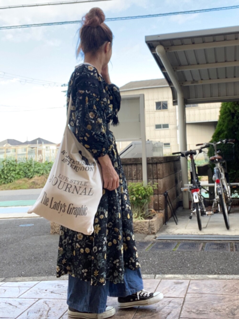 ブラック系のワンピース、ホワイト系のトートバッグ、ブルー系のデニムパンツを着用したレディースの秋コーディネートの1枚目の写真