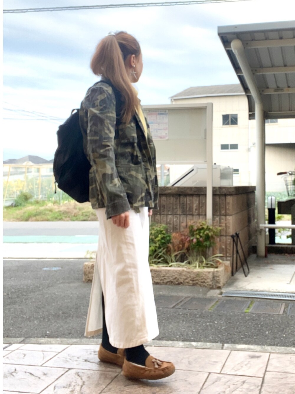 グリーン系のミリタリージャケット、ブラック系のバックパック/リュック、ホワイト系のスカートを着用したレディースの冬コーディネートの1枚目の写真