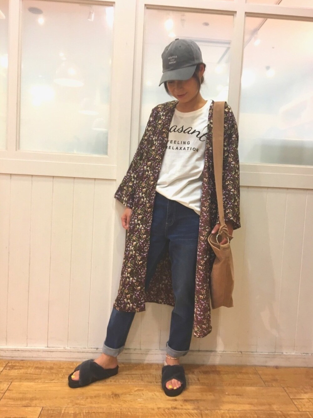 ブルー系のデニムパンツ、グレー系のサンダル、ブラウン系のトートバッグを着用したレディースの夏コーディネートの1枚目の写真