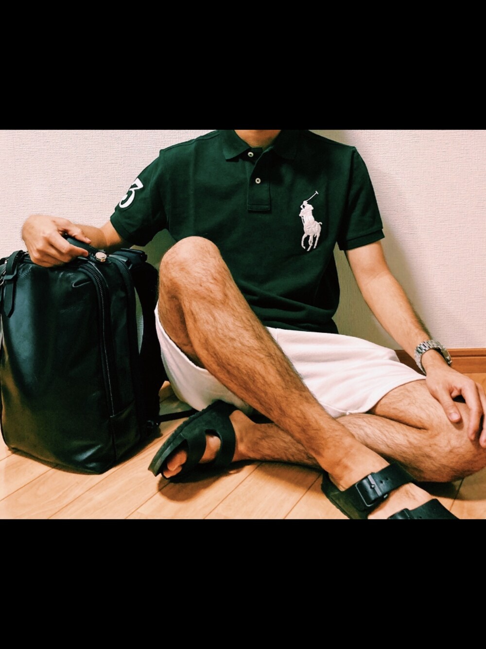 グリーン系のポロシャツ、ホワイト系のパンツ、ブラック系のサンダルを着用したメンズの春コーディネートの1枚目の写真
