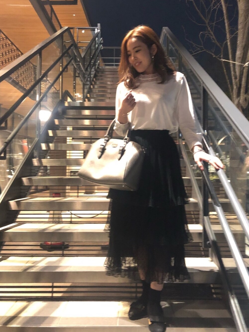 シルバー系のショルダーバッグ、ブラック系のスカート、ホワイト系のTシャツ/カットソーを着用したレディースの春コーディネートの1枚目の写真