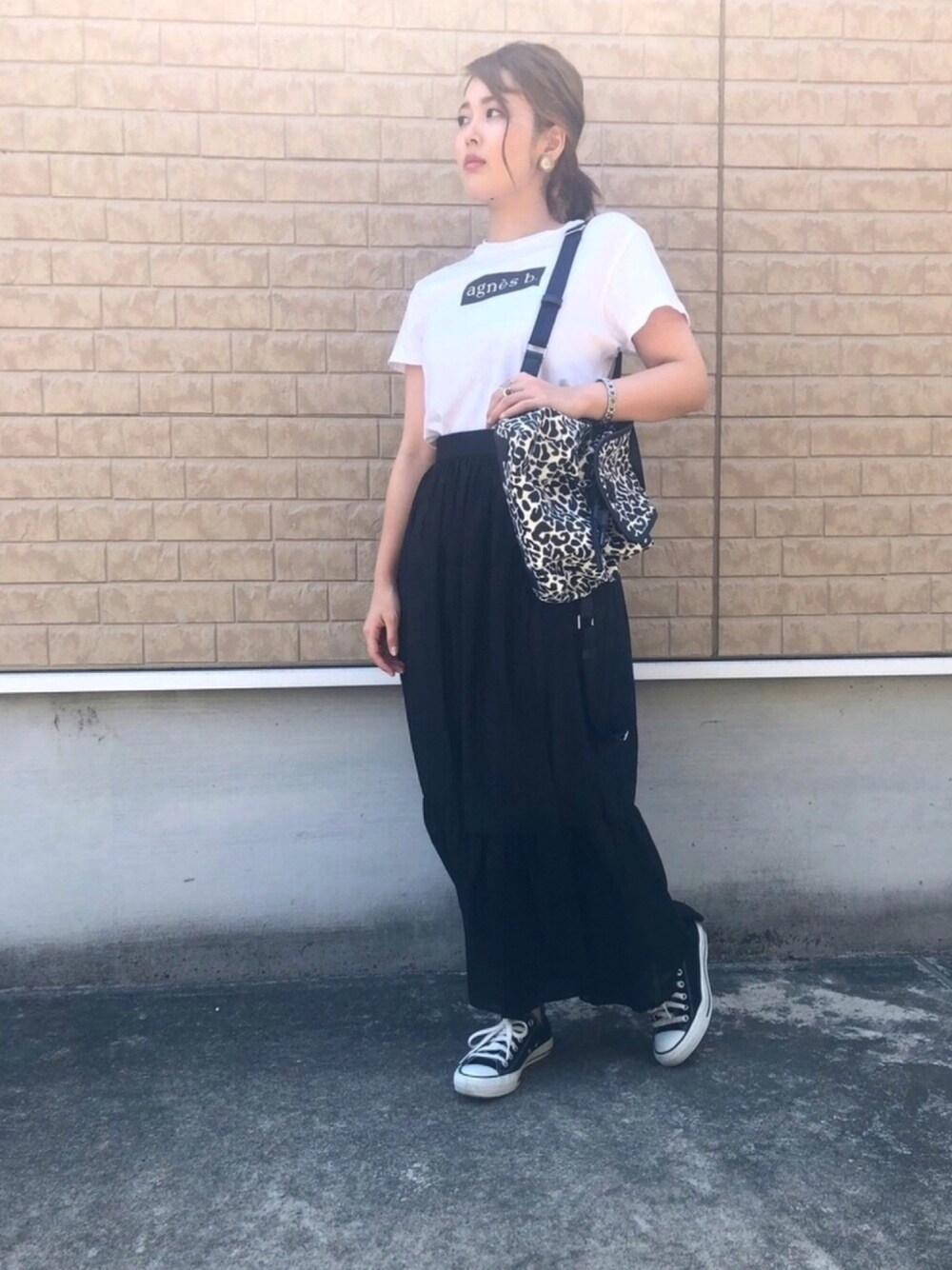 ブラック系のスカート、ホワイト系のTシャツ/カットソー、ブラック系のスニーカーを着用したレディースの夏コーディネートの1枚目の写真