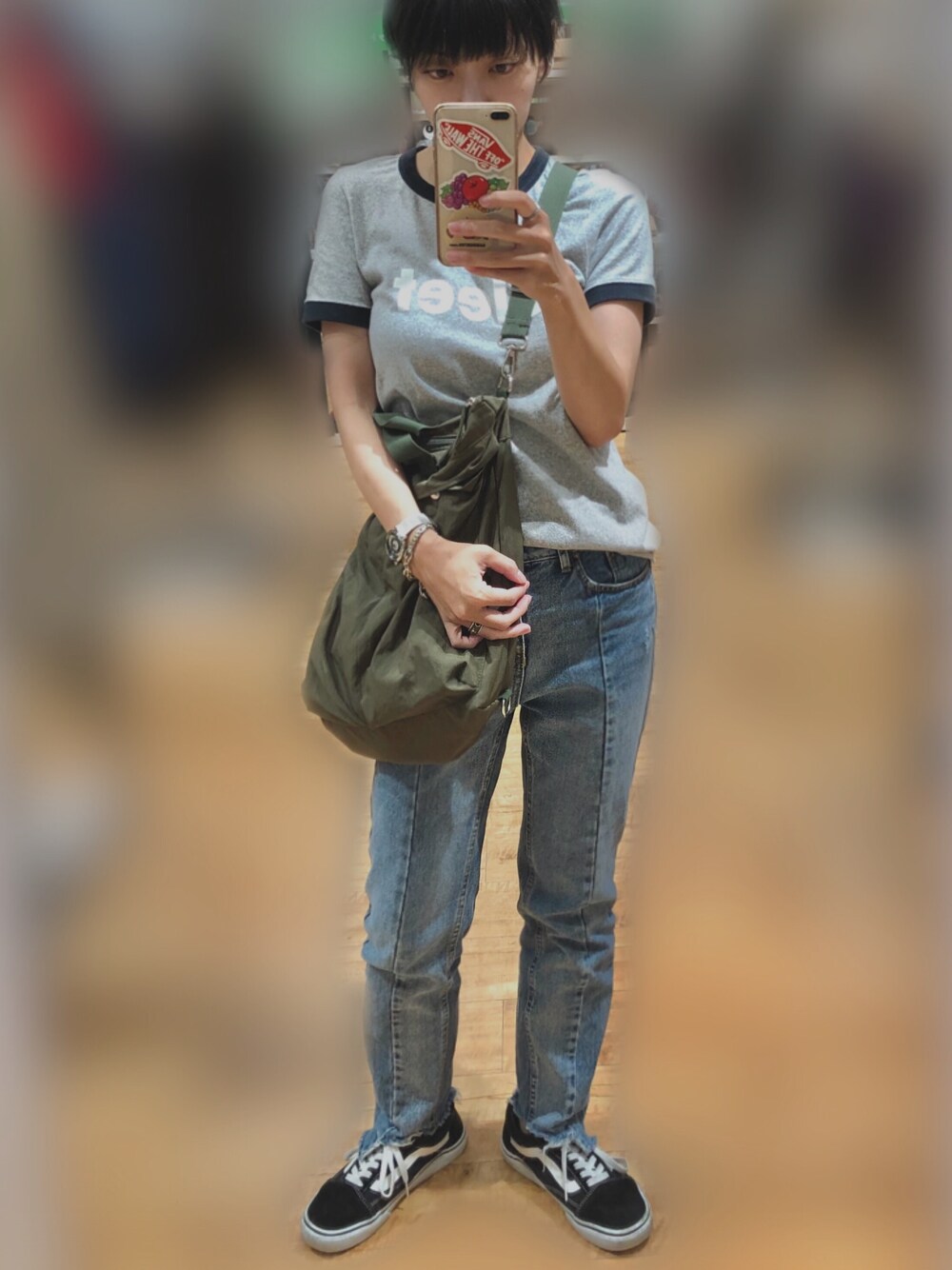 グレー系のTシャツ/カットソー、グリーン系のトートバッグ、ブルー系のデニムパンツを着用したレディースの秋コーディネートの1枚目の写真