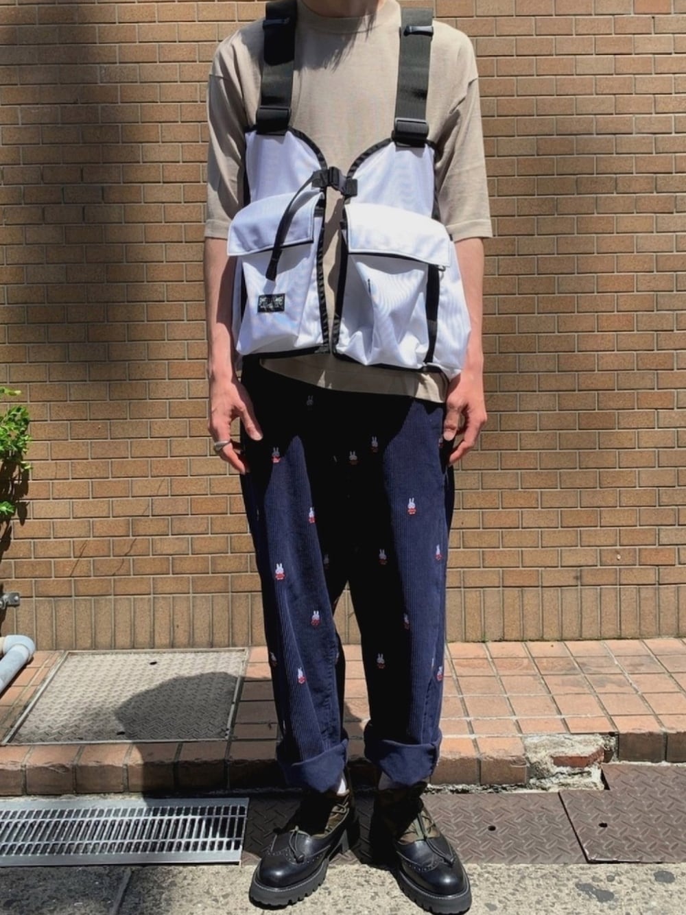 ブラック系のブーツ、ブルー系のパンツ、ホワイト系のベストを着用したメンズの春コーディネートの1枚目の写真
