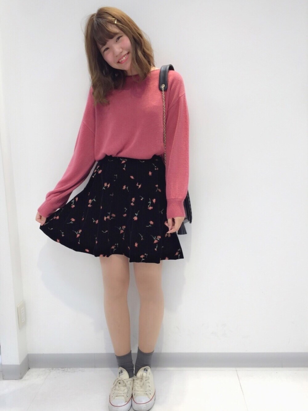 ピンク系のトップス、ブラック系のスカート、ベージュ系のスニーカーを着用したレディースの冬コーディネートの1枚目の写真