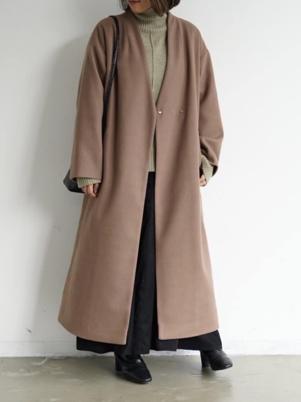 グリーン系のニット/セーター、ブラック系のブーツ、ブラック系のワンピースを着用したレディースの秋コーディネートの1枚目の写真