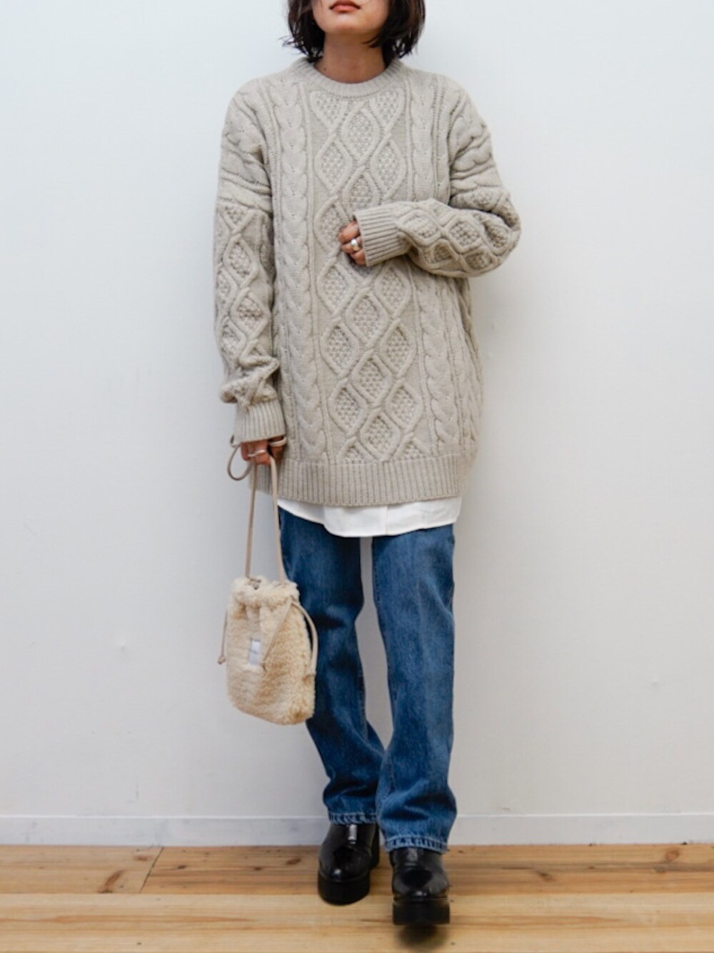 ベージュ系のニット/セーター、ホワイト系のシャツ/ブラウス、ベージュ系のショルダーバッグを着用したレディースの冬コーディネートの1枚目の写真