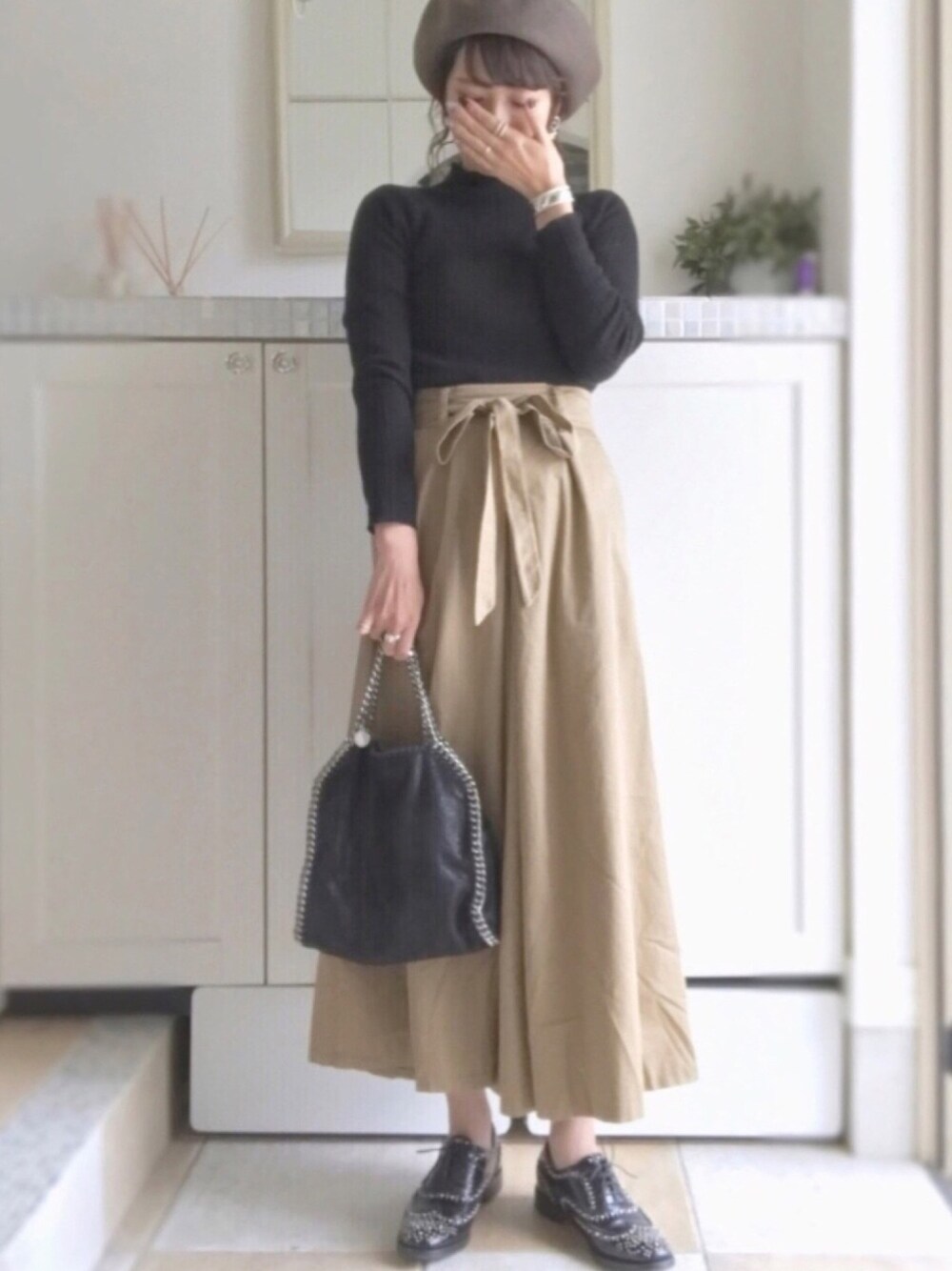 ベージュ系のその他パンツ、ブラック系のニット/セーター、ブラック系のショルダーバッグを着用したレディースの秋コーディネートの1枚目の写真