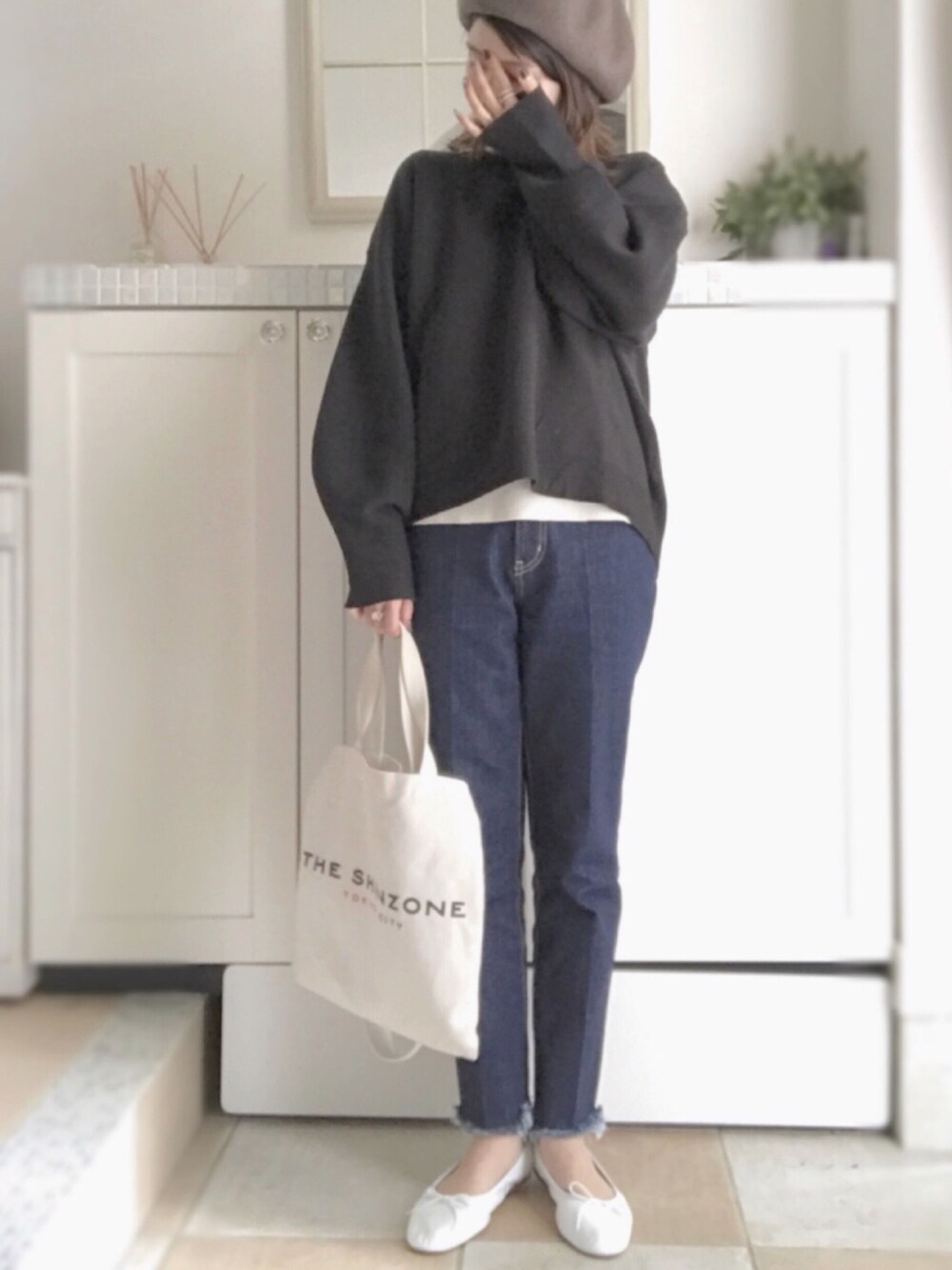 ブルー系のデニムパンツ、ホワイト系のバレエシューズ、ブラック系のニット/セーターを着用したレディースの秋コーディネートの1枚目の写真