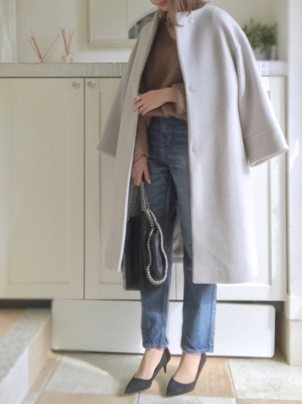 ブラウン系のニット/セーター、グレー系のその他アウター、ブルー系のデニムパンツを着用したレディースの冬コーディネートの1枚目の写真