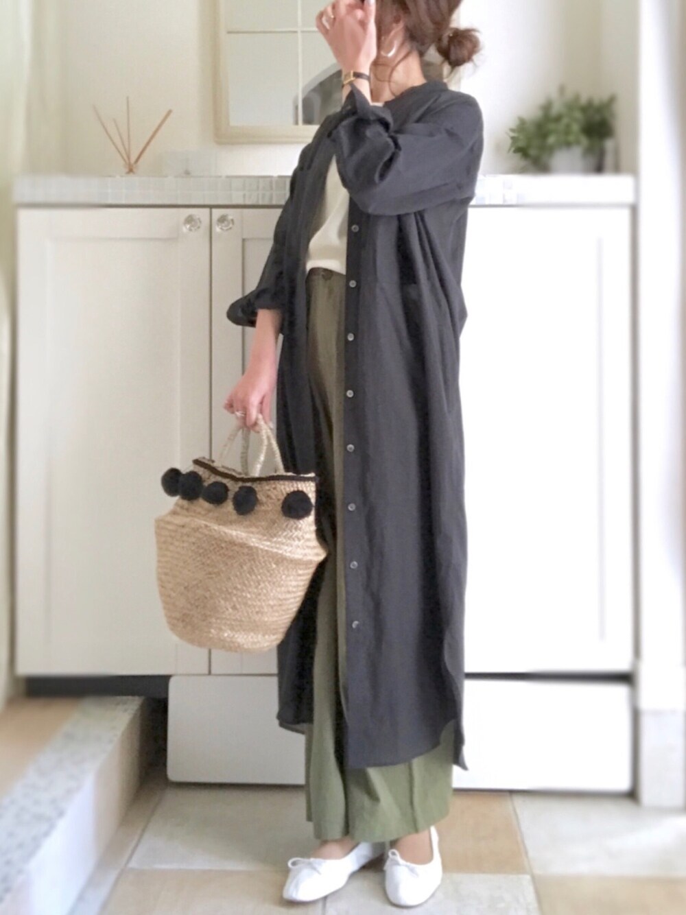 ブラック系のシャツワンピース、ブラック系のかごバッグ、ホワイト系のバレエシューズを着用したレディースの春コーディネートの1枚目の写真