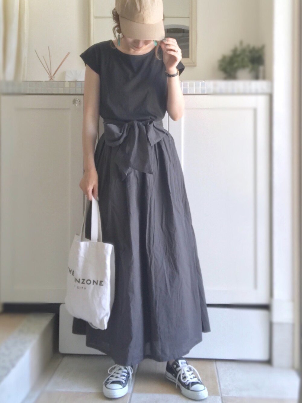 ブラック系のワンピース、ブラック系のスニーカー、ベージュ系のキャップを着用したレディースの夏コーディネートの1枚目の写真