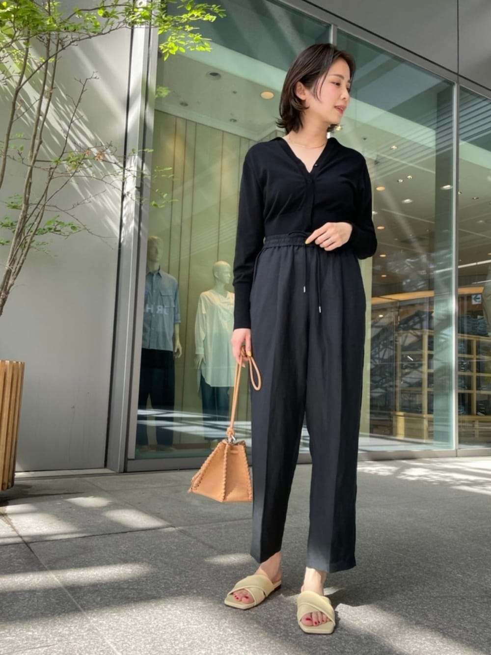 ブラック系のその他パンツ、ブラック系のニット/セーター、イエロー系のサンダルを着用したレディースの春コーディネートの1枚目の写真