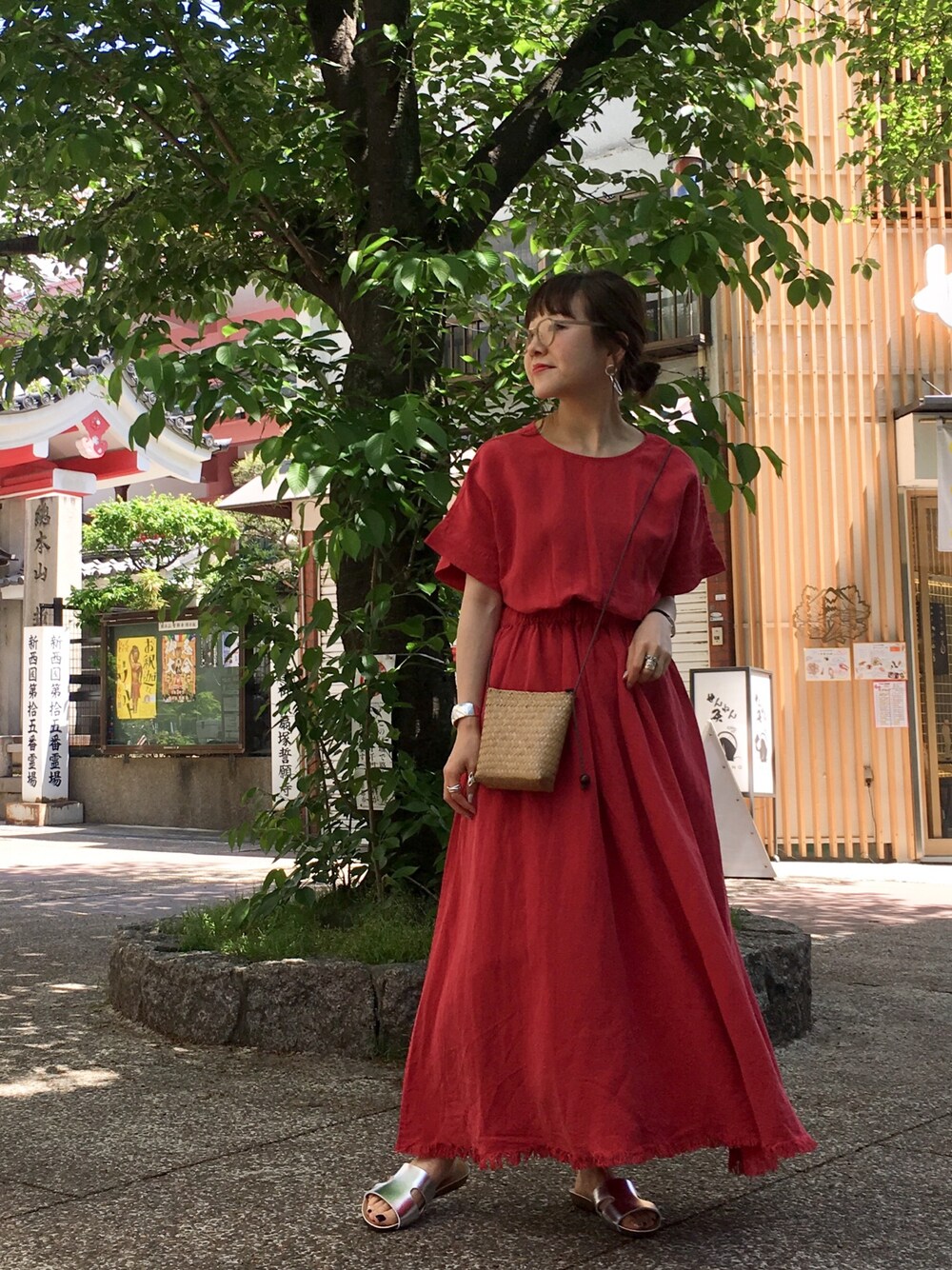レッド系のワンピース、ベージュ系のバッグ、シルバー系のサンダルを着用したレディースの春コーディネートの1枚目の写真