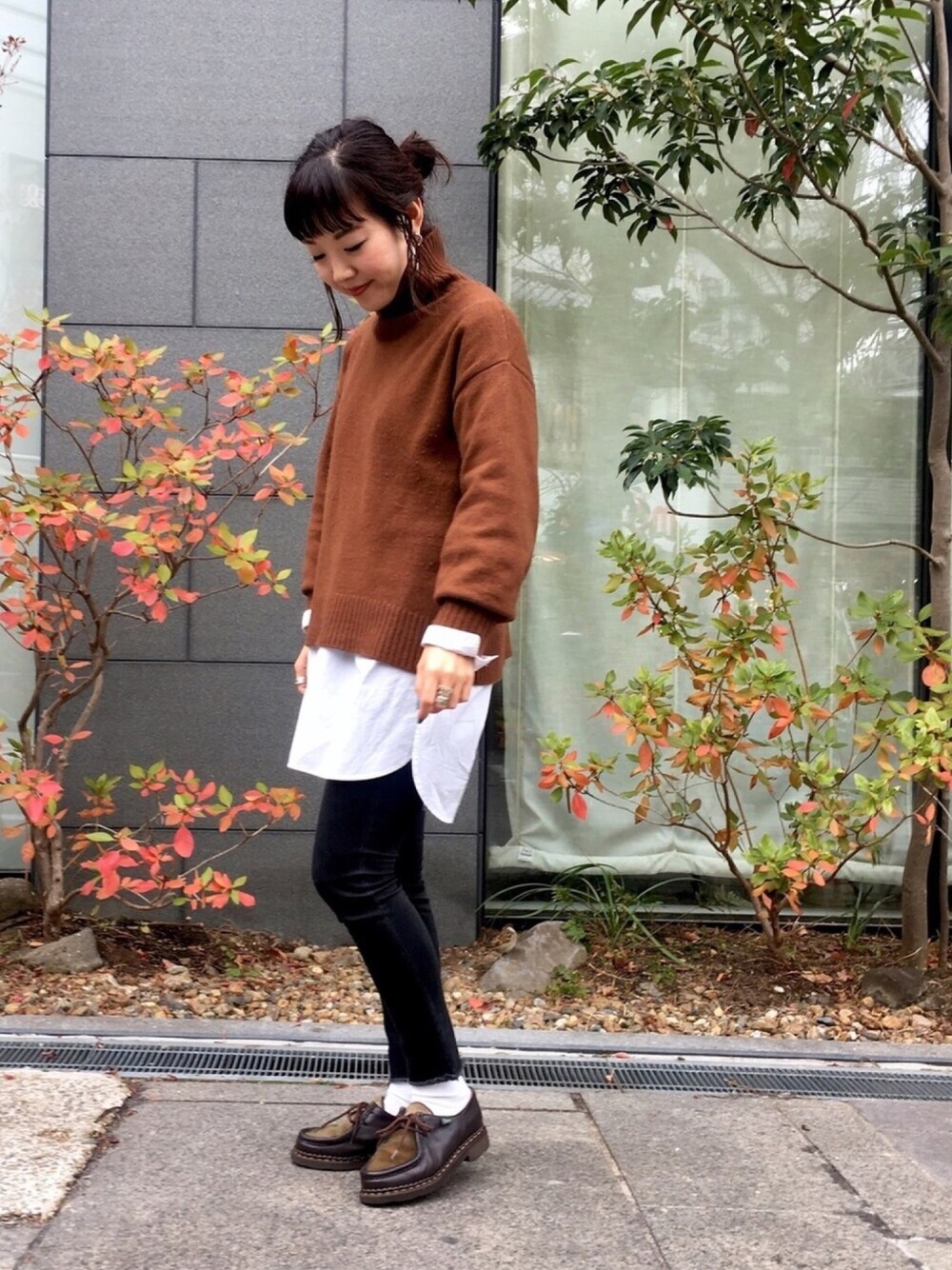 ブラウン系のニット/セーター、ホワイト系のチュニック、ブラック系のデニムパンツを着用したレディースの冬コーディネートの1枚目の写真
