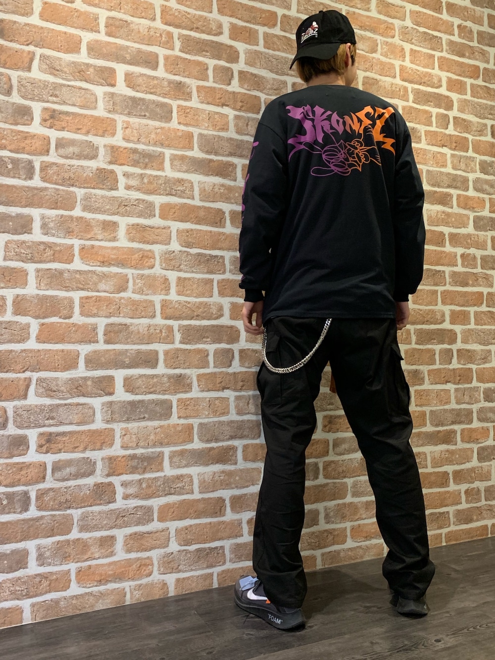 「コラボ、ストリート、LHP、ロンT、オレンジ、差し色、パープル×黒、KaneZ、SKOLOCT、ローキャップ」｜「KaneZのKaneZ×SKOLOCT/ケインズ×スコロクト/SKONEZ ロゴロングスリーブTシャツ（Tシャツ/カットソー、ブラック系）」を使った、山田 統生さん（メンズ・182cm）の春コーディネートの1枚目の写真