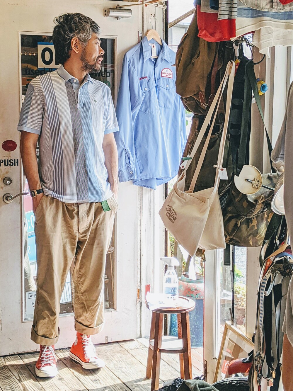 ブルー系のポロシャツ、ベージュ系のチノパンツ、ブルー系のスニーカーを着用したメンズの春コーディネートの1枚目の写真