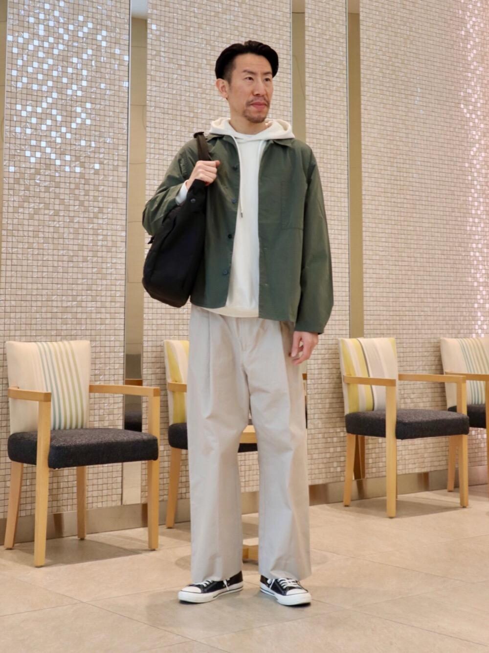 ブラック系のトートバッグ、ホワイト系のパーカー、グリーン系のその他アウターを着用したメンズの春コーディネートの1枚目の写真