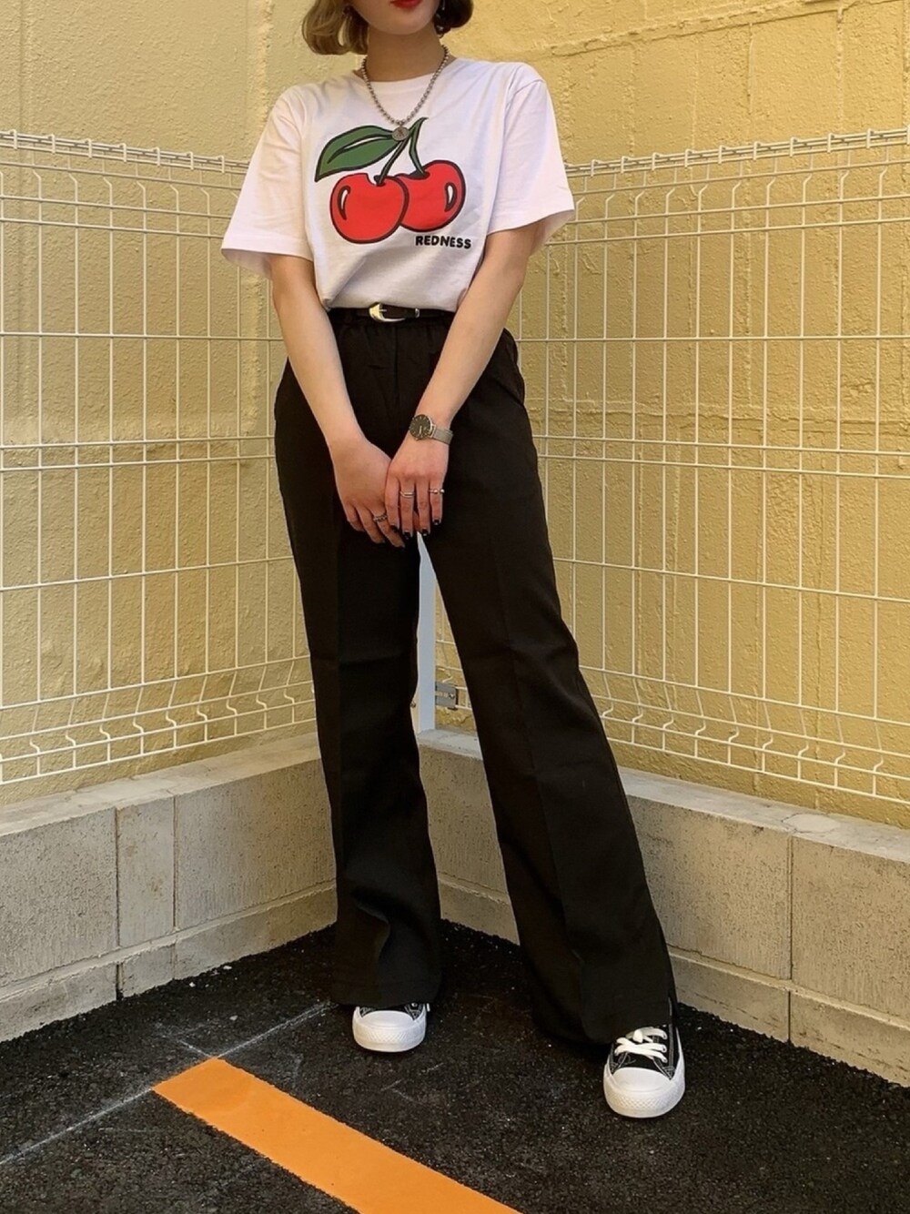 ブラック系のスニーカー、ホワイト系のTシャツ/カットソー、ブラック系のスラックスを着用したレディースの春コーディネートの1枚目の写真
