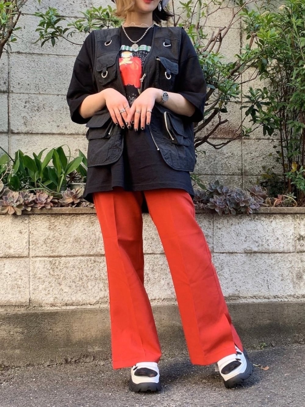 レッド系のスラックス、ホワイト系のサンダル、ブラック系のTシャツ/カットソーを着用したレディースの春コーディネートの1枚目の写真