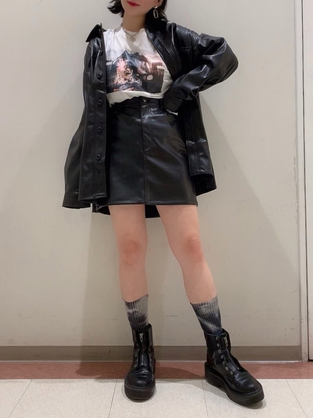 ブラック系のスカート、ブラック系のミリタリージャケット、ホワイト系のTシャツ/カットソーを着用したレディースの秋コーディネートの1枚目の写真
