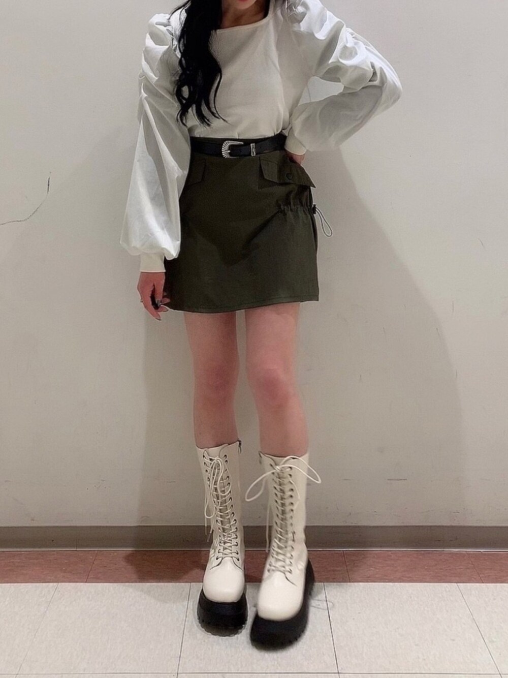 ホワイト系のTシャツ/カットソー、グリーン系のスカート、ホワイト系のブーツを着用したレディースの冬コーディネートの1枚目の写真