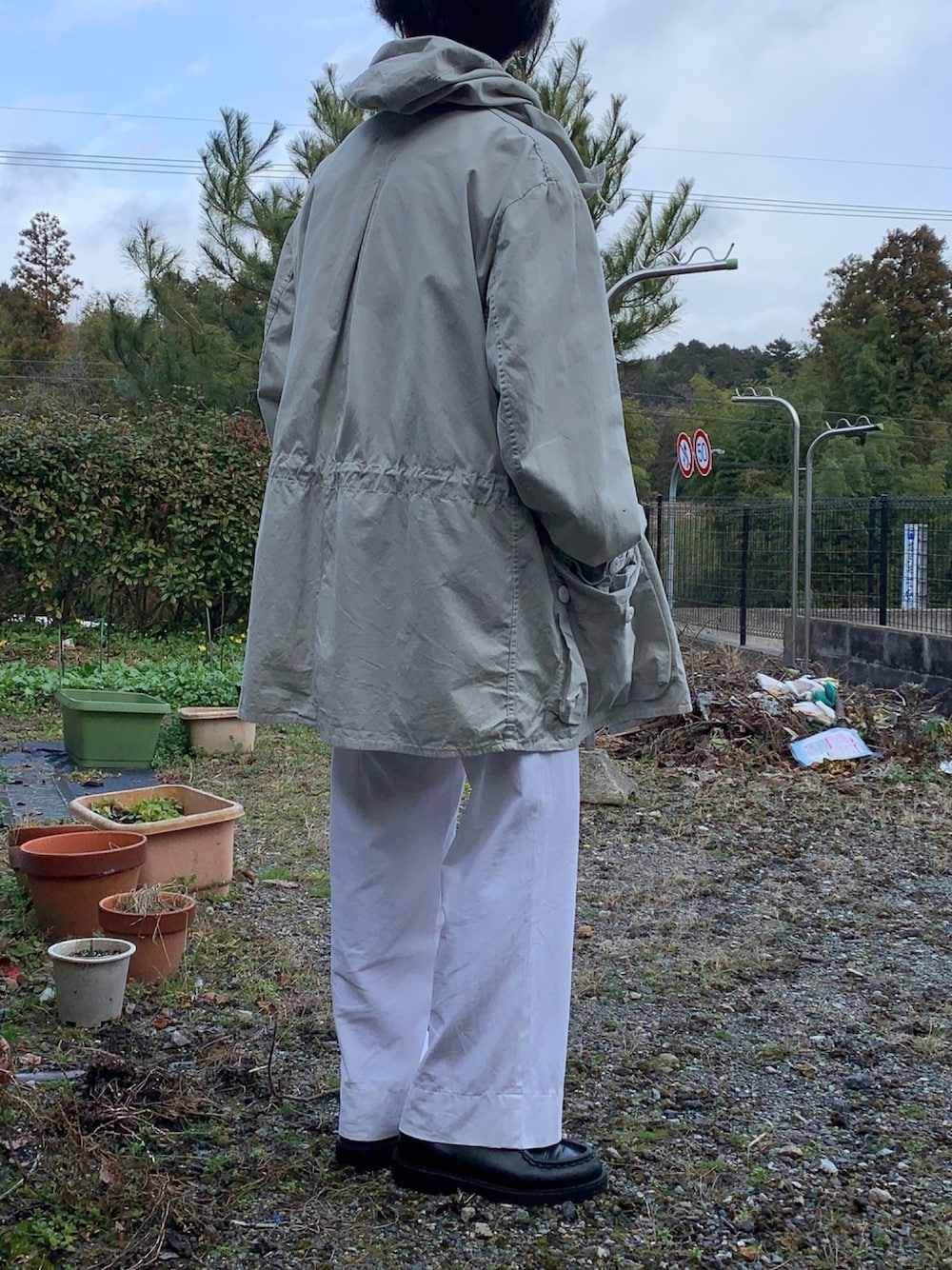 グレー系のマウンテンパーカー、ホワイト系のパンツ、ブラック系のブーツを着用したメンズの冬コーディネートの1枚目の写真