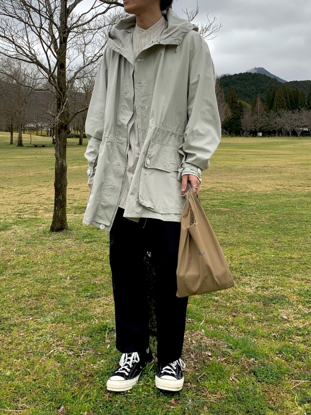 グレー系のマウンテンパーカー、ホワイト系のシャツ/ブラウス、ブラック系のスラックスを着用したメンズの春コーディネートの1枚目の写真