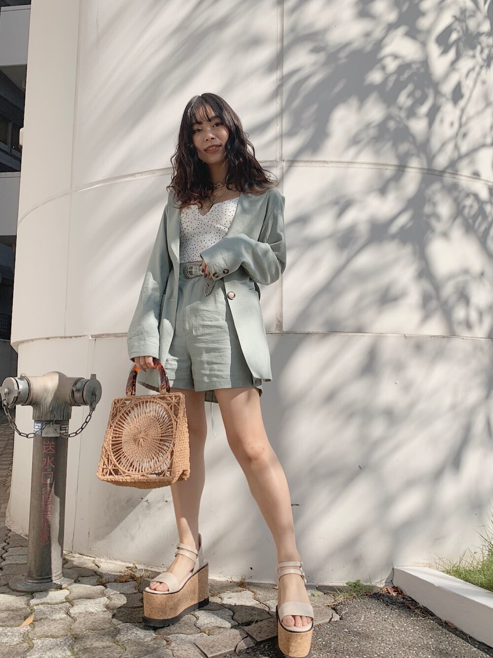 グリーン系のテーラードジャケット、グリーン系のその他パンツ、ベージュ系のハンドバッグを着用したレディースの春コーディネートの1枚目の写真