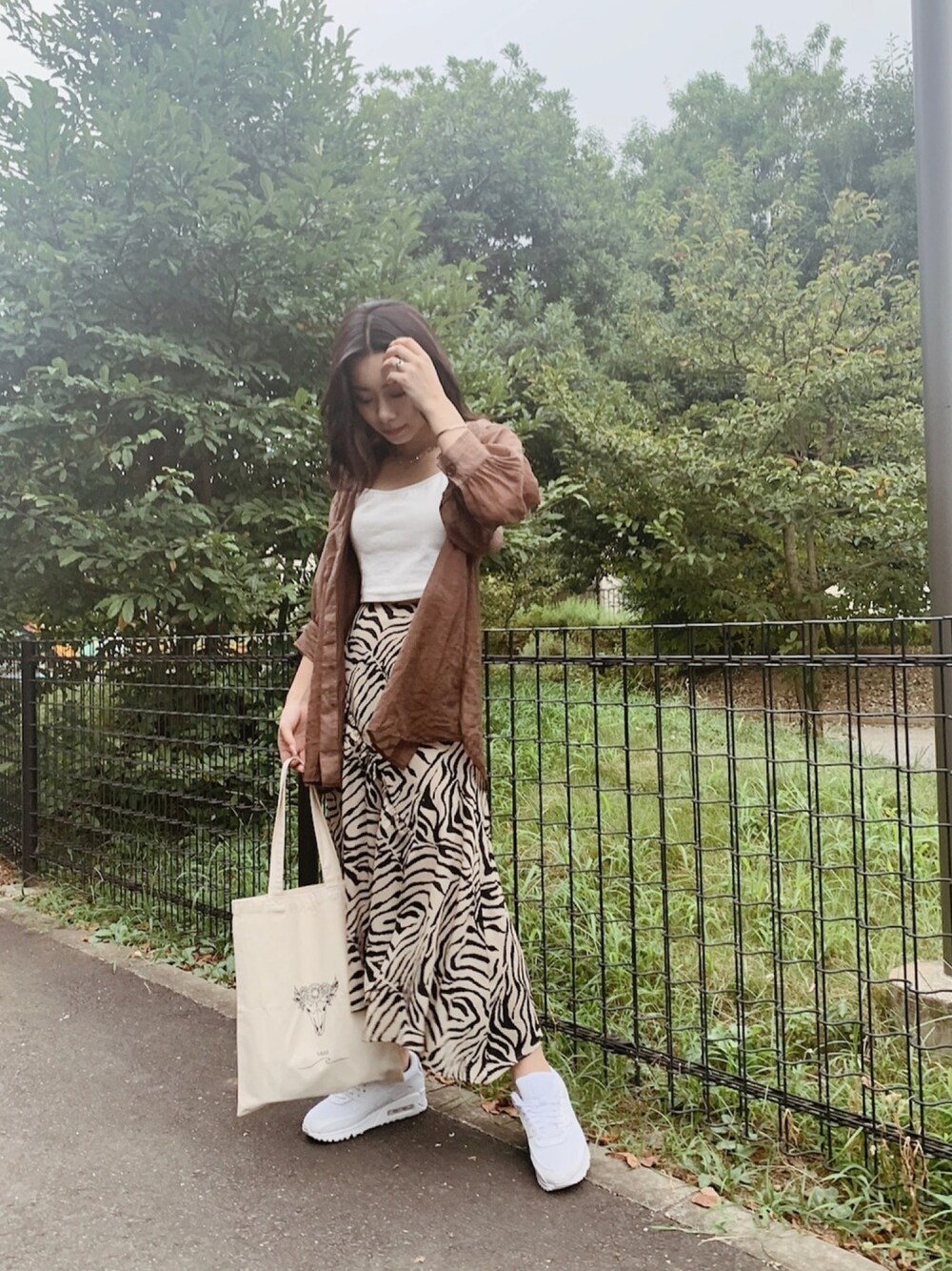 ホワイト系のトップス、ベージュ系のスカート、ホワイト系のスニーカーを着用したレディースの夏コーディネートの1枚目の写真