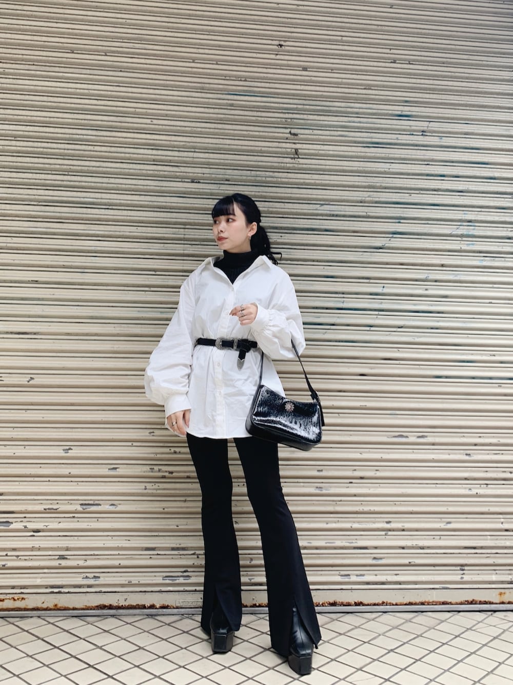 ブラック系のニット/セーター、ホワイト系のシャツ/ブラウス、ブラック系のショルダーバッグを着用したレディースの春コーディネートの1枚目の写真