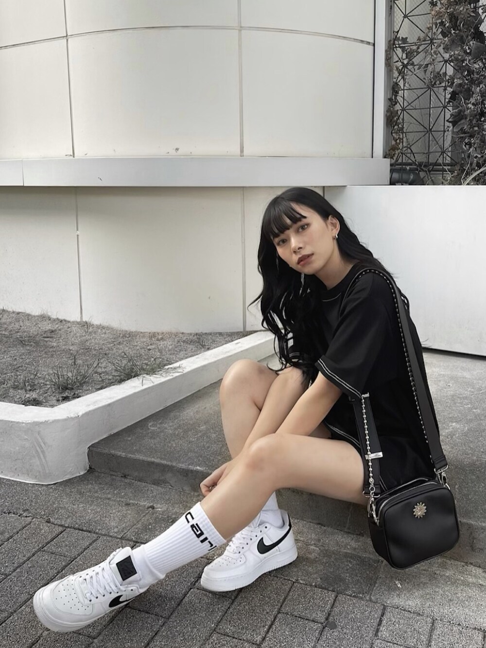 ブラック系のTシャツ/カットソー、ブラック系のショルダーバッグ、ホワイト系のシューズを着用したレディースの春コーディネートの1枚目の写真